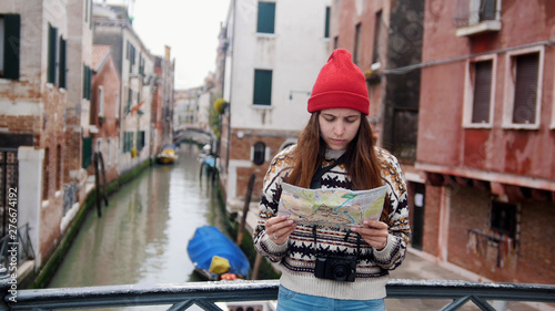 A young woman standing above the water channel and looking at the map - Venice, Italy
