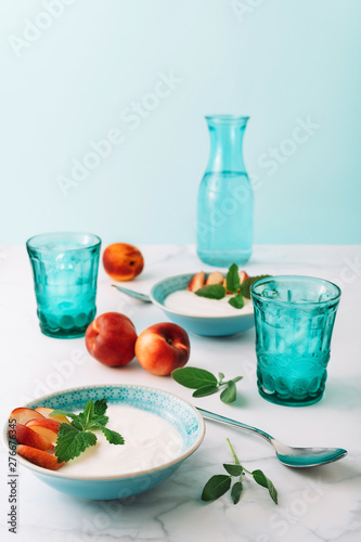 Healthy breakfast concept of natural greek yoghurt, fruit and water on marble table. Close-up.