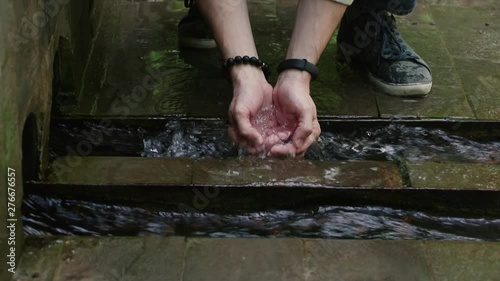 MEN'S HANDS WITH WATCHES AND BRACELET GET WATER FROM THE SPRING, LAYED BY BRICKS