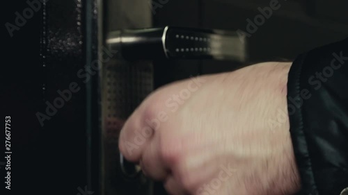 A man's hand opens the door with a key, a man in a black leather jacket enters inside, the door closes, close up