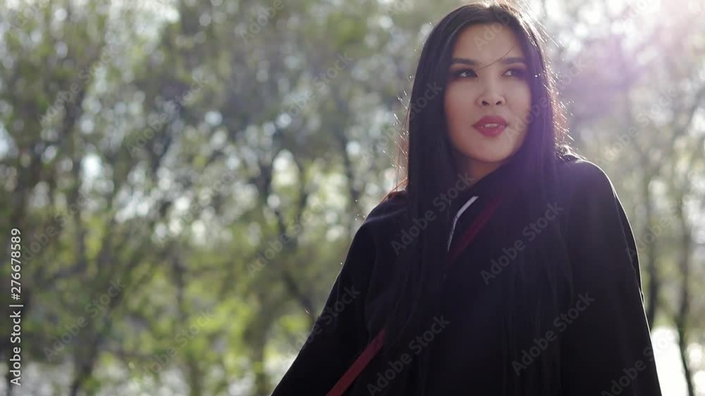 Beautiful young Asian girl with long black hair sitting at the park at the summertime. Soft sunlight on the background. Beautiful young Asian girl with long black hair sitting at the park at the summertime. Soft sunlight on the background.