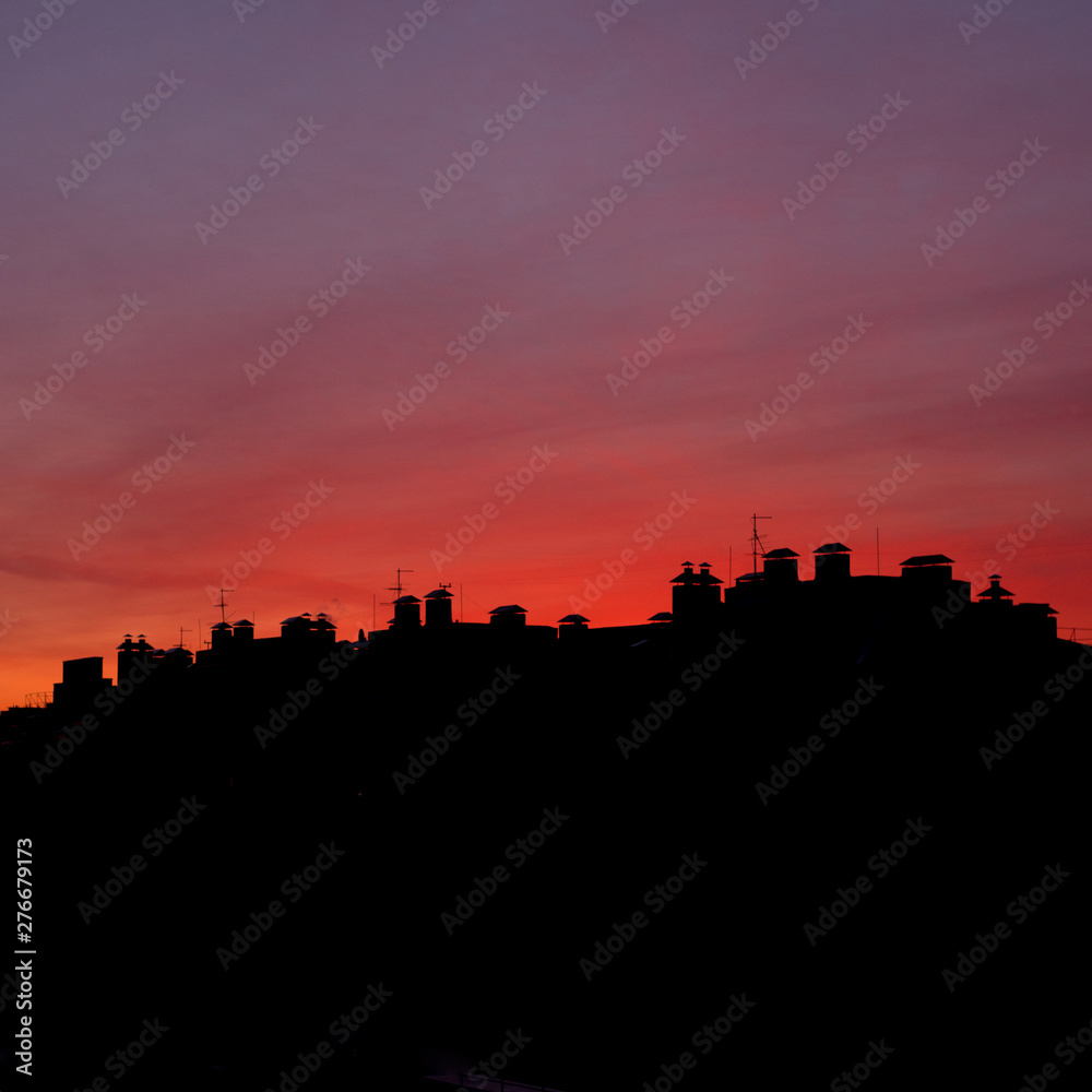 Roofs of houses on a background of red sunset