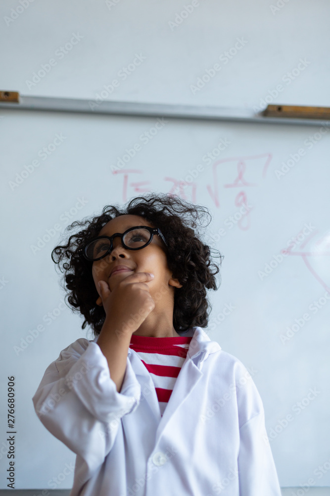 Thoughtful schoolboy with hand on chin standing in laboratory Thoughtful schoolboy with hand on chin standing in laboratory