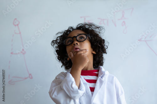 Mixed-race Schoolboy in chemistry coat standing in the laboratory