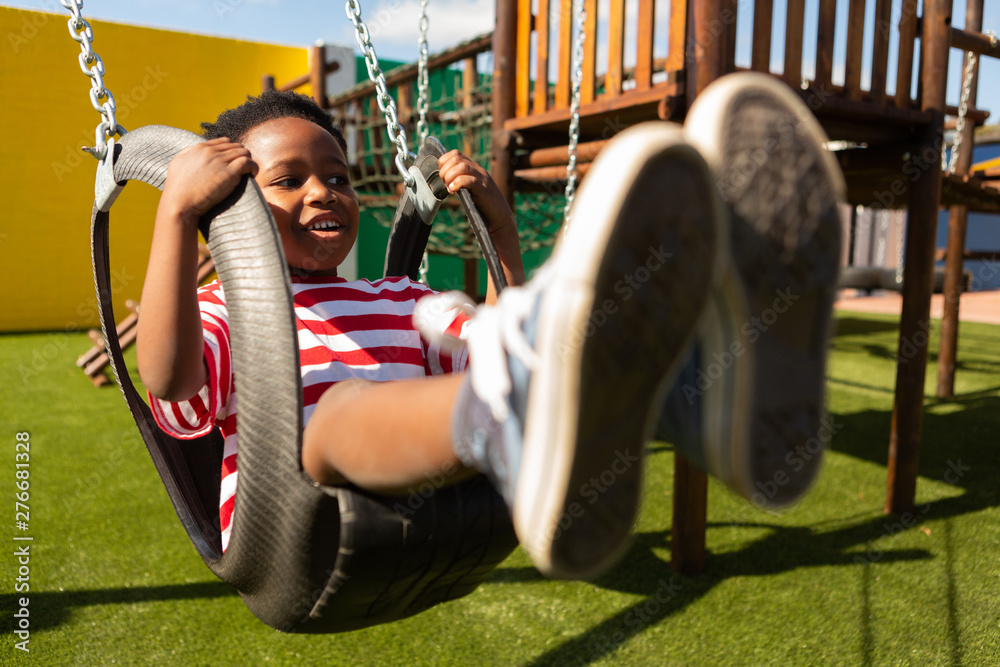 Obraz premium Schoolboy playing on a swing at school playground