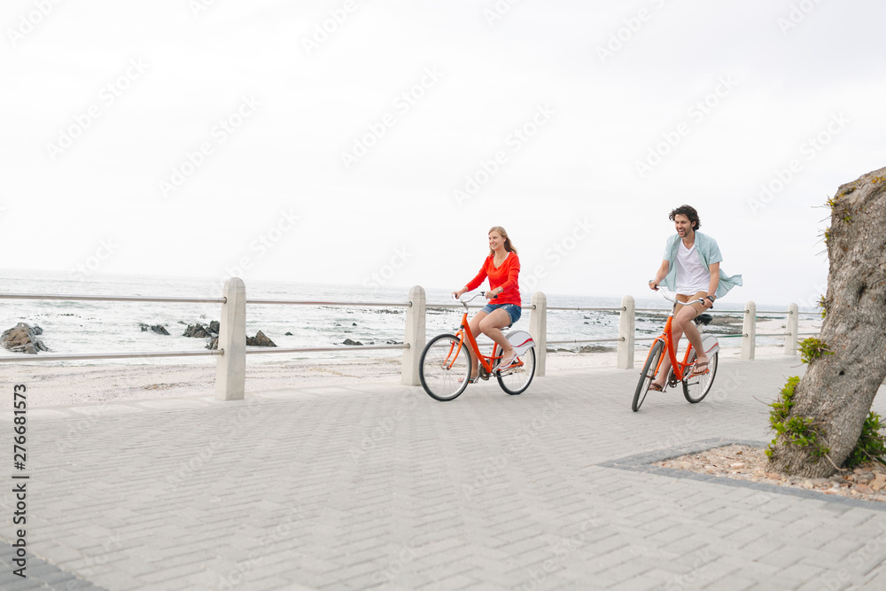 Fototapeta premium Caucasian couple riding bicycle on pavement near promenade 