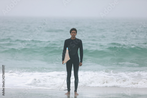 Male surfer running on the beach with surfboard