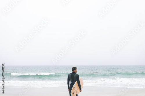 Male surfer holding surfboard on the beach