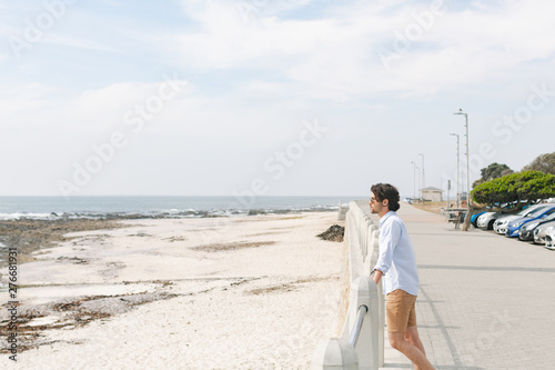 Caucasian man standing near sea side at promenade on a sunny day