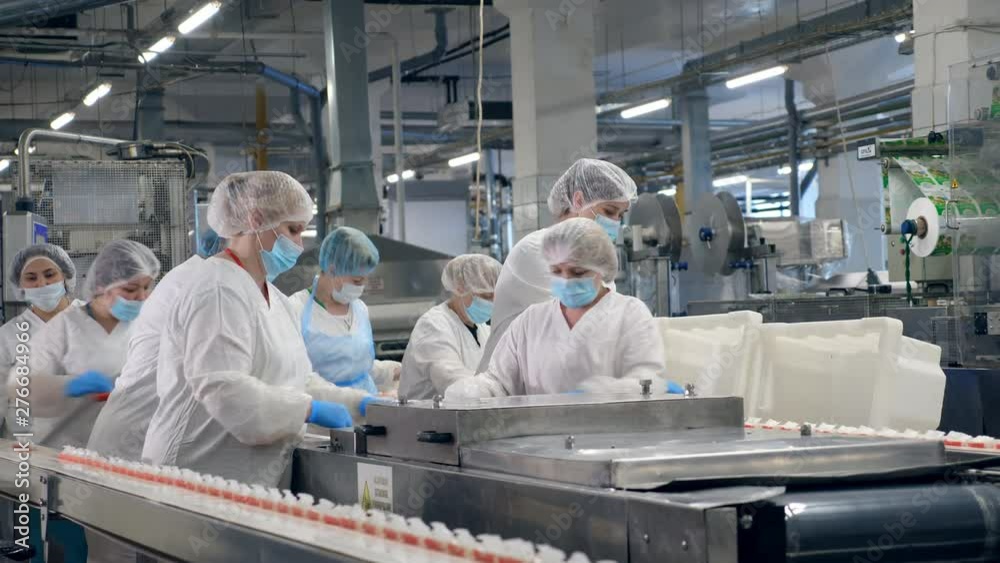 Food factory equipment with women relocating packaged food. Food factory equipment with women relocating packaged food.