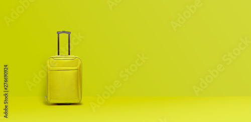 Lime green suitcase standing next to the color wall. Concept travel