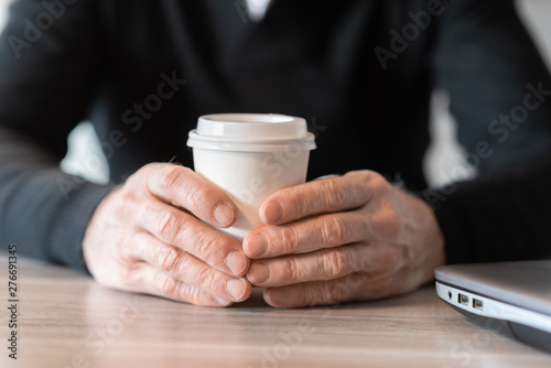 Businessman holding a paper coffee cup