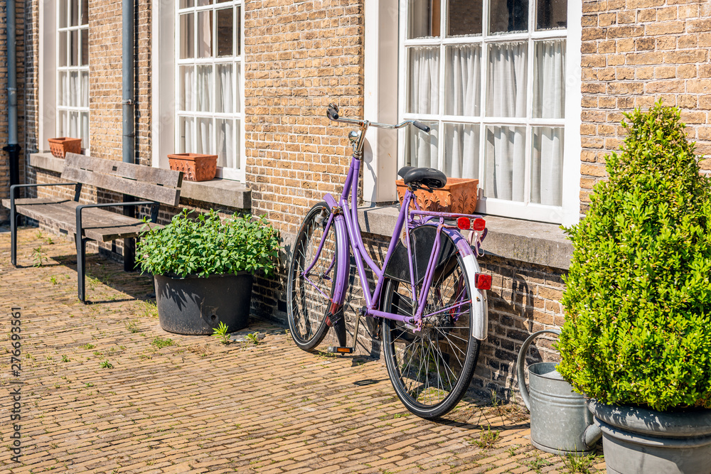 Violet ladies bike against a brick wall