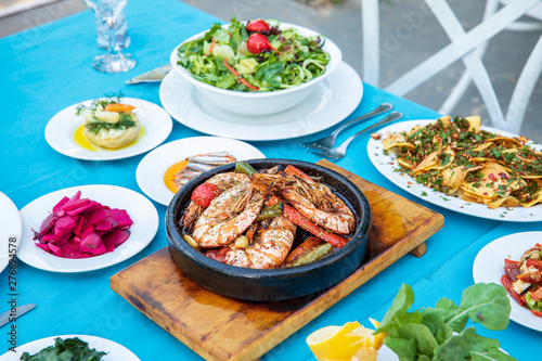 Shrimp, Seafoods, appetizers and salads on the table in Fish Restaurant. Beach Restaurant in Greece or Turkey. Aegean seaside, Greek or Turkish style fish restaurant in Bodrum, Santorini or Mykonos