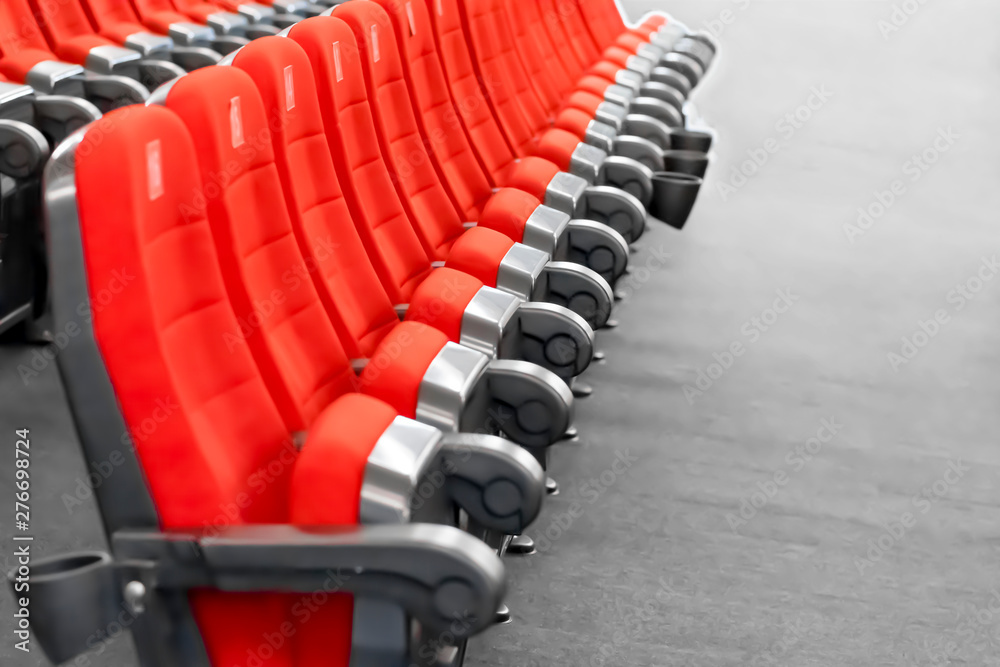 Fototapeta premium A row of red seats on the gray floor of the modern cinema hall.