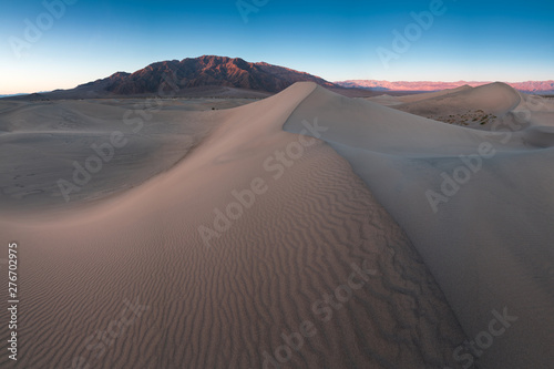 Early Morning Sunlight Over Sand Dunes And Mountains At Mesquite flat dunes, Death Valley National Park, California USA Stovepipe Wells sand dunes, very nice structures in sand Beautiful background