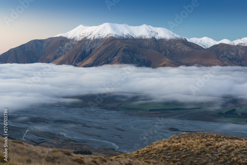 The valley is flooded in mist in a mountain environment. Over the fogs  only the high peaks of the mountains rise beneath the sunny sky. Misty morning. Beuatiful landscape concept.