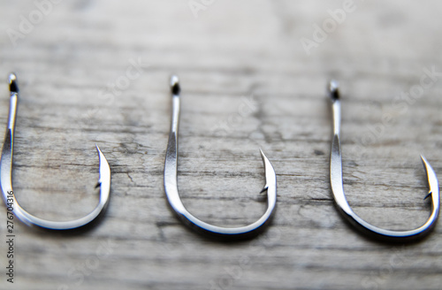 Fishing hook on a gray wooden board, close-up