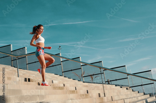 Towards a healthier lifestyle. Full length of beautiful young woman in sports clothing running while exercising outdoors © gstockstudio