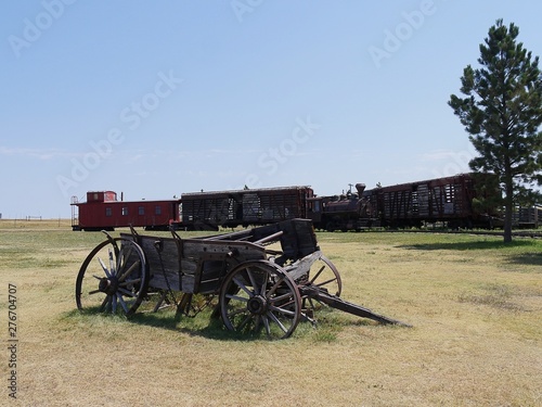 Wide shot of a dilapidated wooden wagon cart and old railway train displayed at an 1880s town in South Dakota.