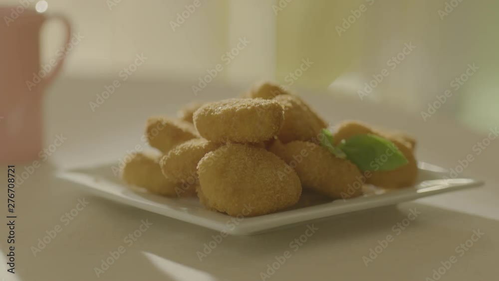 The child's hand takes an appetizing nuggets from the plate. Very beautiful studio shot. Slow motion. Camera Arri Alexa.