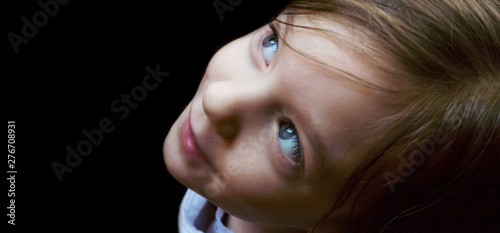 Isolated closeup of a three-year-old Caucasian girl’s profile as she stares slightly upward with awe and curiosity.