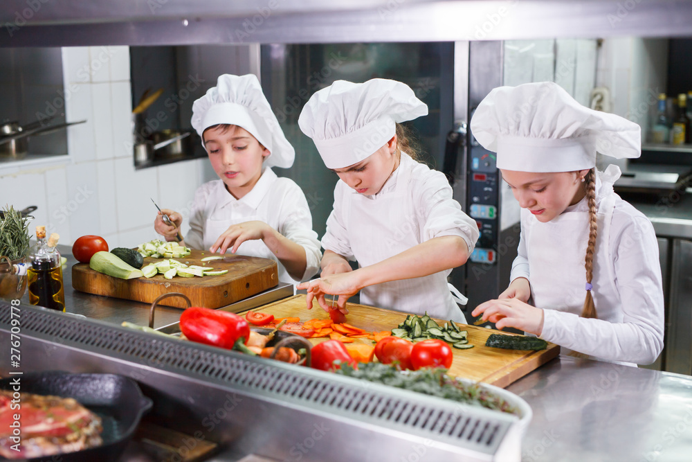 children cooking lunch in a restaurant kitchen. children cooking lunch in a restaurant kitchen.