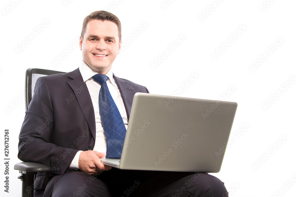 A smiling businessman holds a laptop while sitting in a chair. Close-up. A smiling businessman holds a laptop while sitting in a chair. Close-up.