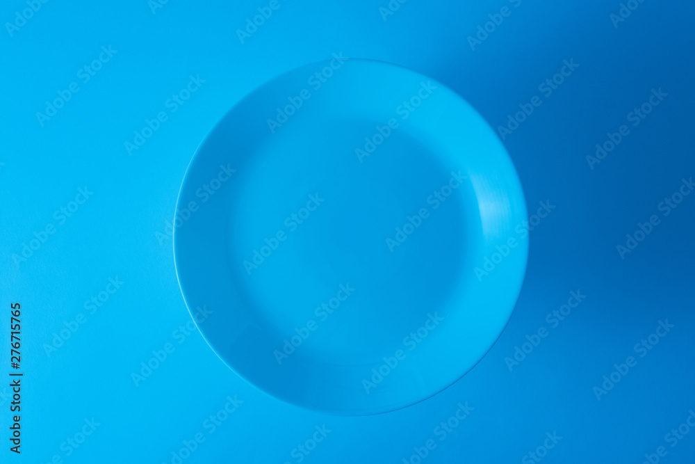 An overhead view of empty blue plate against blue background An overhead view of empty blue plate against blue background