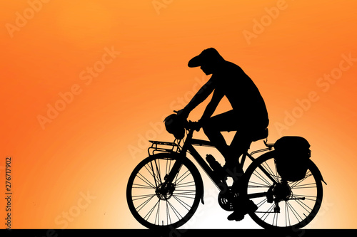 Silhouette cycling on blurry sunrise sky background.