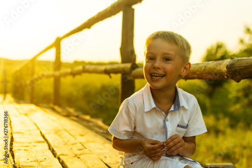 boy plays on an old wooden bridge on a bright warm evening at sunset