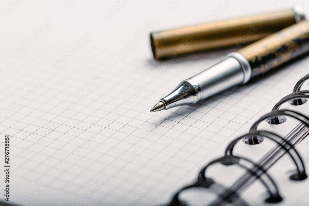 Opened notepad in a cage with an automatic plastic ballpoint pen close-up. toned Opened notepad in a cage with an automatic plastic ballpoint pen close-up. toned