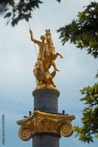 Gilded statue of St. George against the cloudy sky,