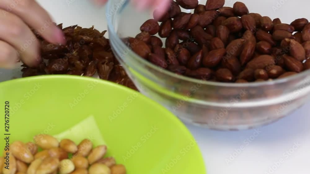 Woman peels almonds, scalded with boiling water. Close-up. Almonds for the filling of sweets glazed with chocolate. Woman peels almonds, scalded with boiling water. Close-up. Almonds for the filling of sweets glazed with chocolate.