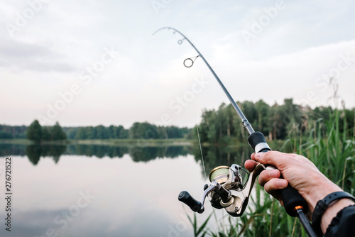 Fisherman with rod, spinning reel on the river bank. Fishing for pike, perch, carp. Fog against the backdrop of lake. background Misty morning. wild nature. Article about fishing day.