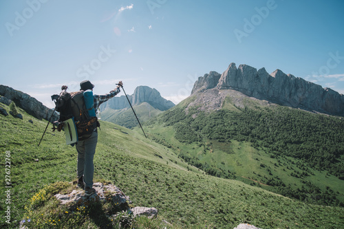  young guy with a tourist backpack looks at the mountain peaks on a sunny summer day