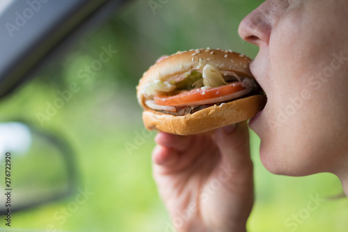 Woman eating a hamburger in the car.