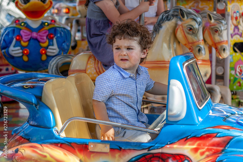 Niño sentado en el coche de un parque infantil