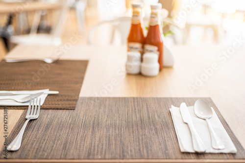 Close-up of luxurious spoon and fork, flower vaseson, sauce bottle the dining table decoration in hotel photo