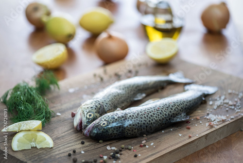 Raw trout on the table with a slice of lemon, salt and spices.
