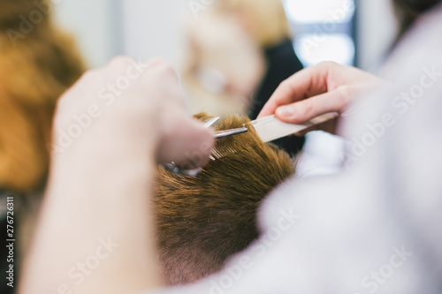 Barber Making Haircut Bearded Man In Barbershop. Professional stylist cutting client hair in salon. Barber using scissors and comb. Skillful hairdresser cutting male hair. Hair Care Service Concept