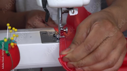 North American woman sewing Canadian red and white flag. Preparetion for July 1st, Canada day. Close up of  the hands, sewing machine, thread and lace, handmade, machine needle at work process. 4k. photo