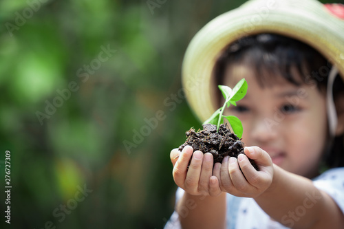 Asian kid holding the young green plant in hand. Ecology and safe world concept.