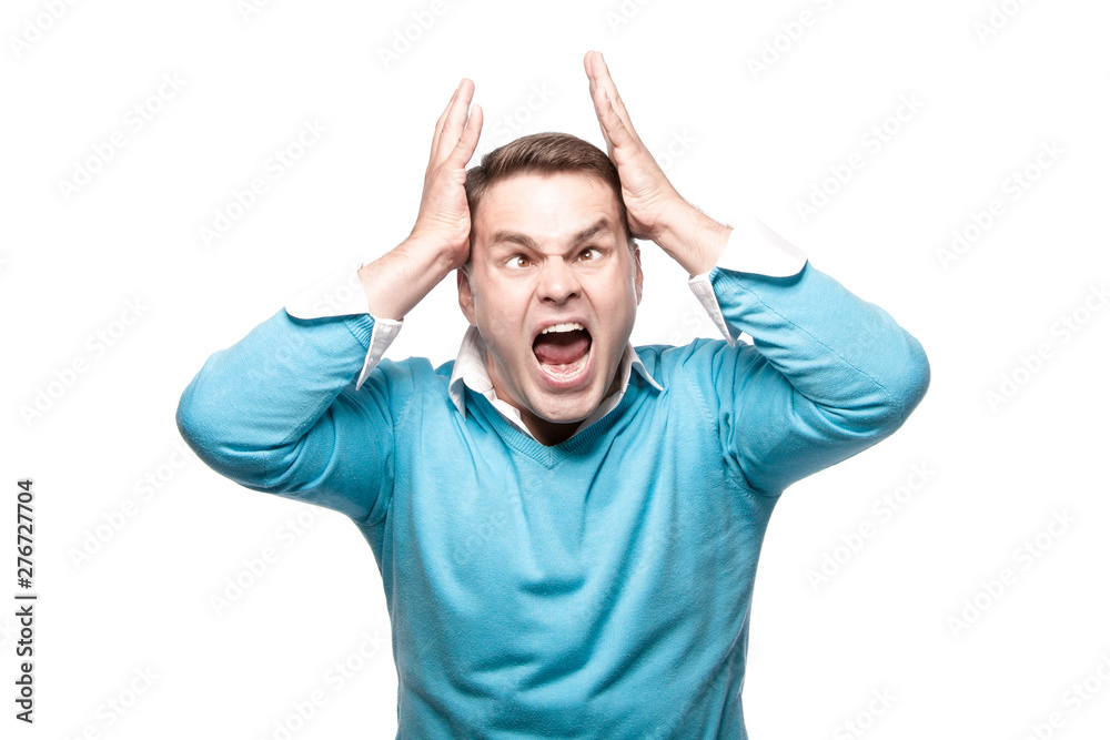 A screaming young man has a headache. On a white background in the studio. A screaming young man has a headache. On a white background in the studio.