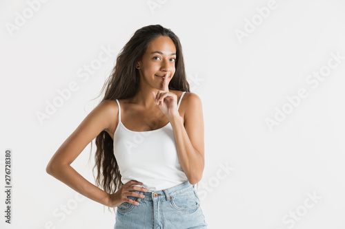 Beautiful female half-length portrait isolated on white studio background. Young emotional african-american woman with long hair. Facial expression, human emotions concept. Whispering a secret.