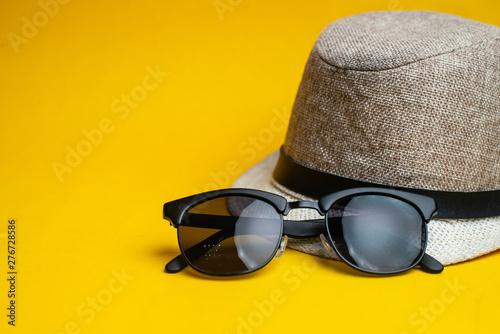 Summer accessories, hat and sun glasses on yellow background. Summer vacation and sea concept.