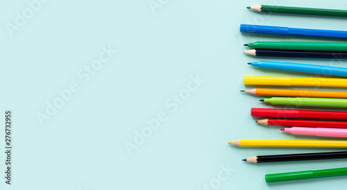 Multicolored pencils on a soft blue background, top view, copy space.
