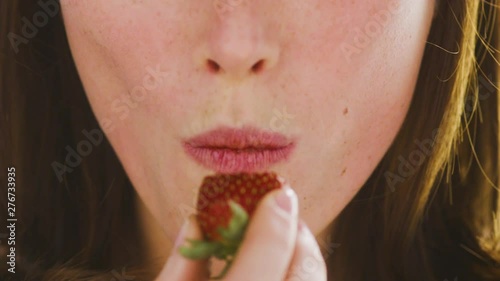 Beautiful, female lips with appetite eat ripe strawberries. Close up.Very beautiful studio shot. Slow motion. Camera Arri Alexa.