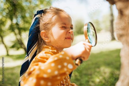 Fototapeta Curious kid with magnifying glass exploring the nature outdoor