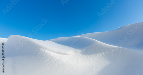Snow dunes caused by drifting snow and the wind in winter with bright sunlight